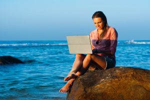 Woman on beach working on laptop