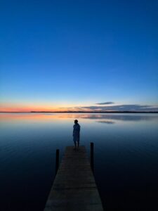 woman looking out over a calm ocean sunset